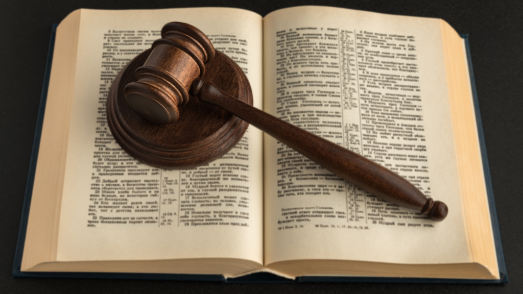 A legal book that is open with a judges wooden gavel laying on top of the opened book.