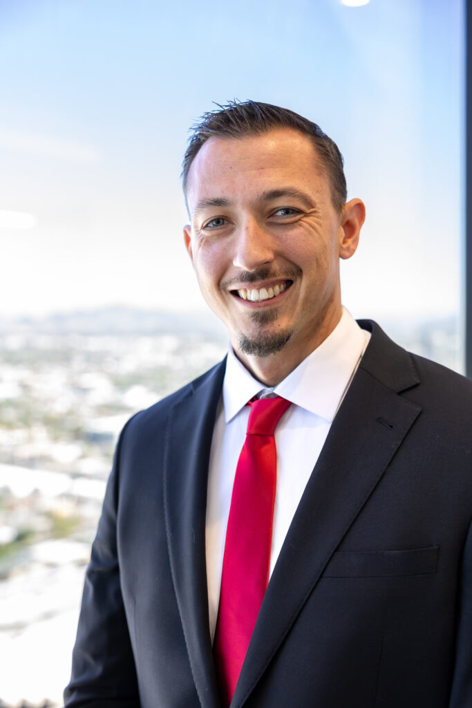 Attorney Tim Krupnik standing in front of his law office window overlooking downtown Phoenix, Arizona.